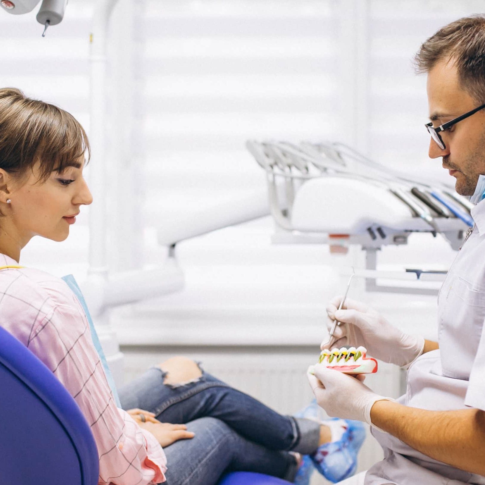 Dentiste expliquanbt à une jeune femme les soins qui lui seront prodigués