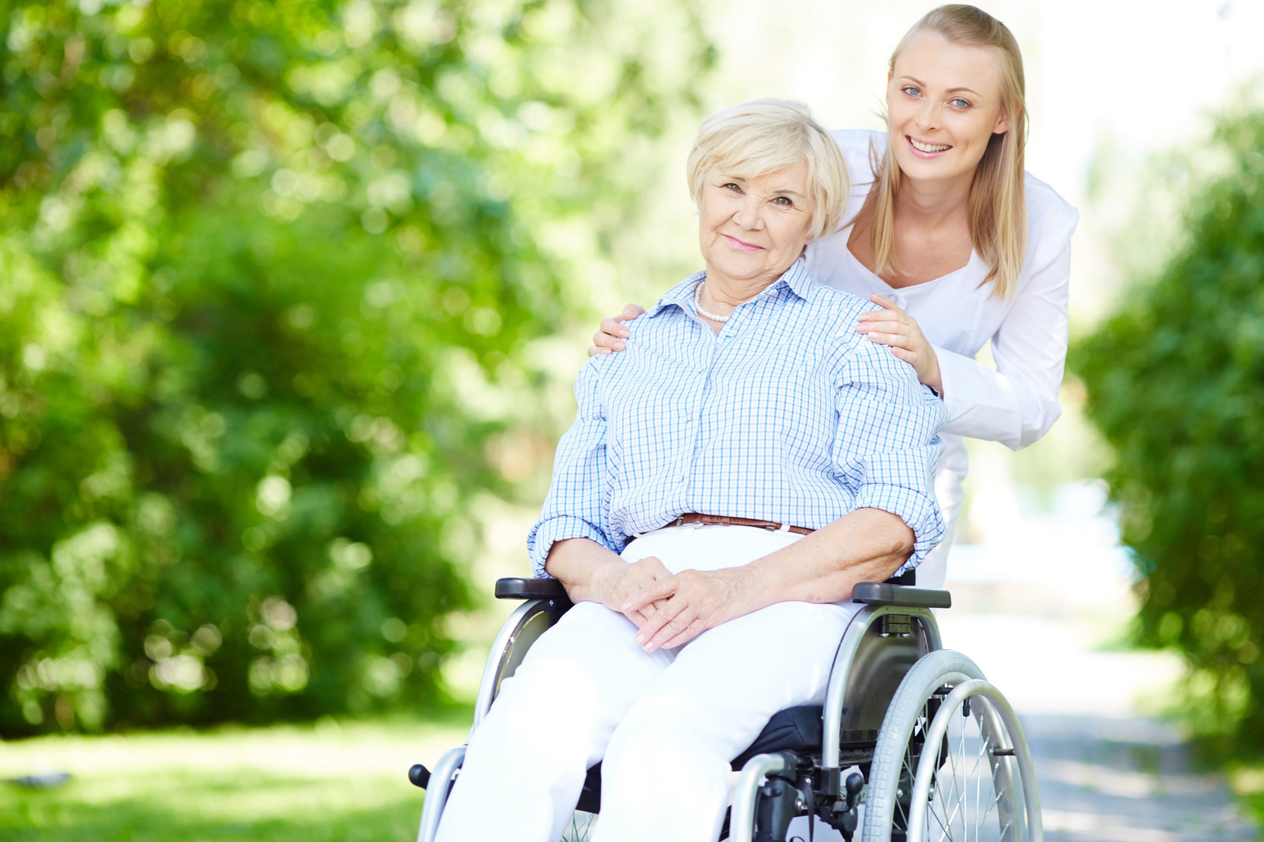 jeune femme poussant le fauteuil roulant d'une personne âgée dans un parc ensoleillé