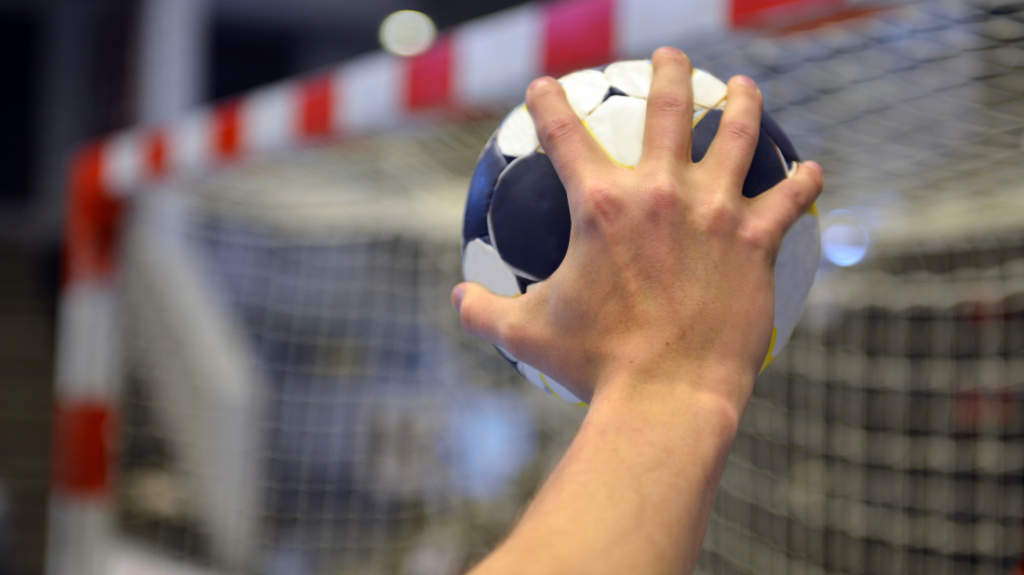 gros plan de la main d'un handballeur qui tient un ballon et prêt à viser le but