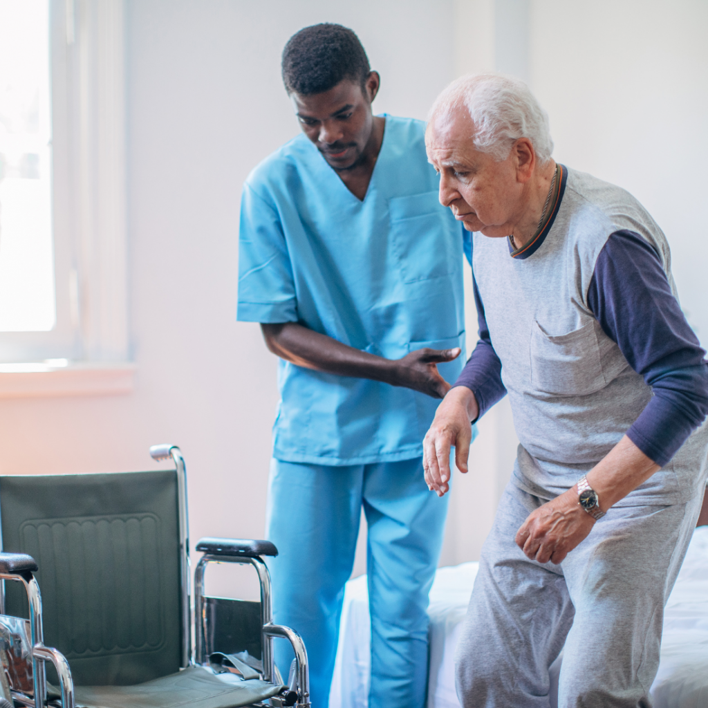 Infirmier professionnel de santé en blouse bleu aidant un homme âgé à rejoindre son fauteuil roulant