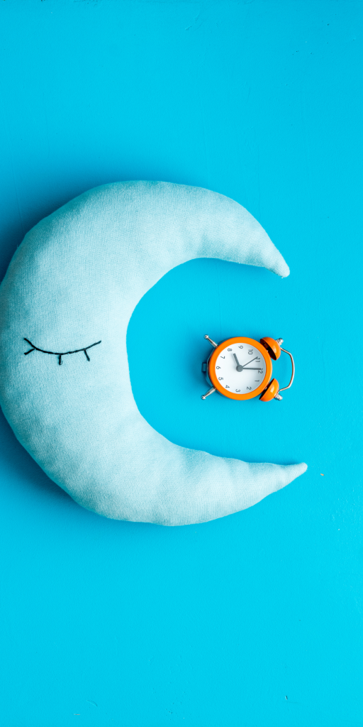 lune turquoise sur fond bleu faisant face à un réveil illustrant les trouvbles du sommeil