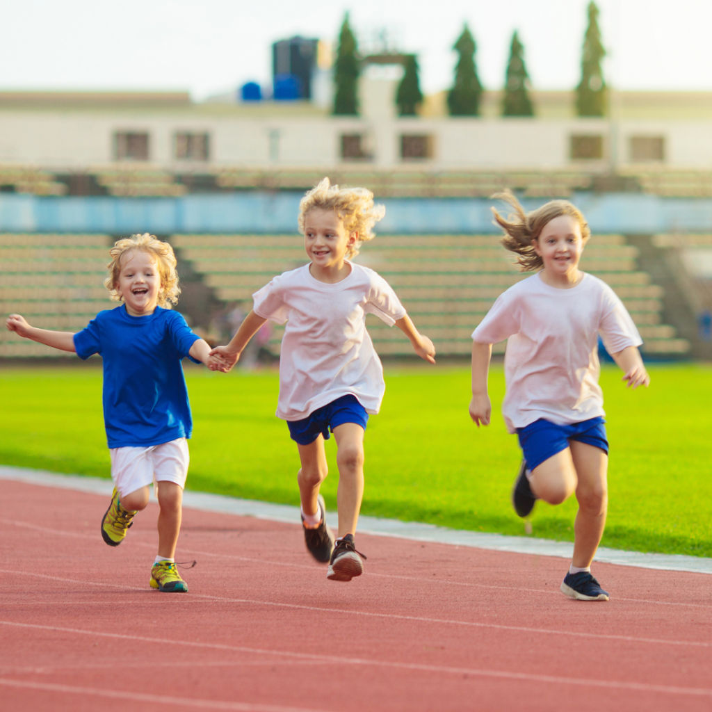 3 jeunes enfants faisant du sport et courant sur une piste d'athlétisme