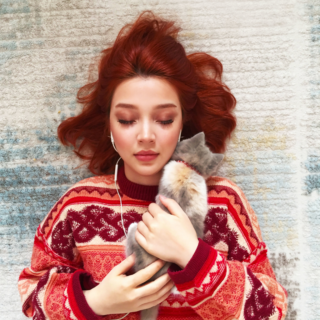 bienfait n° 4 - Jeune femme rousse écoutant de la musique et tenant dans ses bars un petit chat
