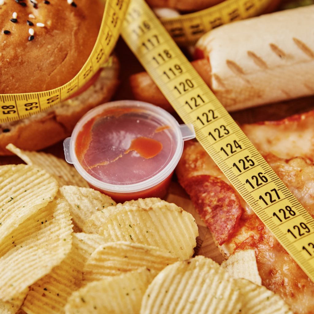 Malbouffe avec chips, pizzas, ketchup et un mètre ruban 