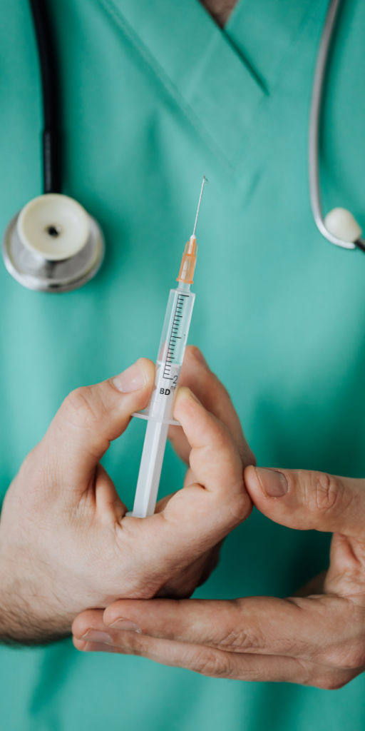 Médecin en blouse verte tenant une dose de vaccination contre la COVID-19