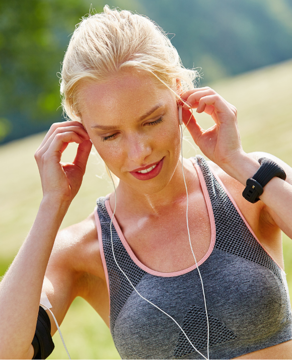Jeune femme blonde avec ses écouteurs et en tenue de training prête à la pratique de son activité sportive favorite
