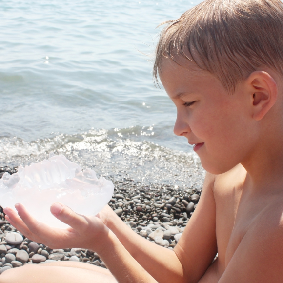 enfant sur la plage tenant une méduse échouée