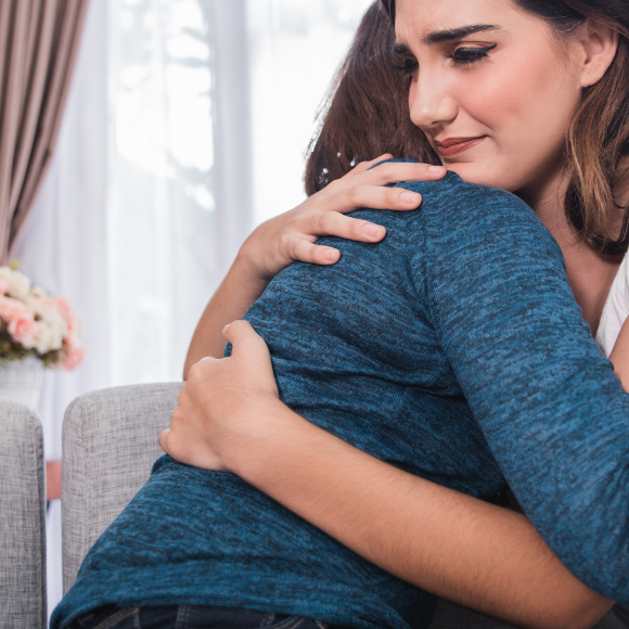 Fmmes de serrant dans les bras de l'un de l'autre se réconfortant suite à des pensées suicidaires