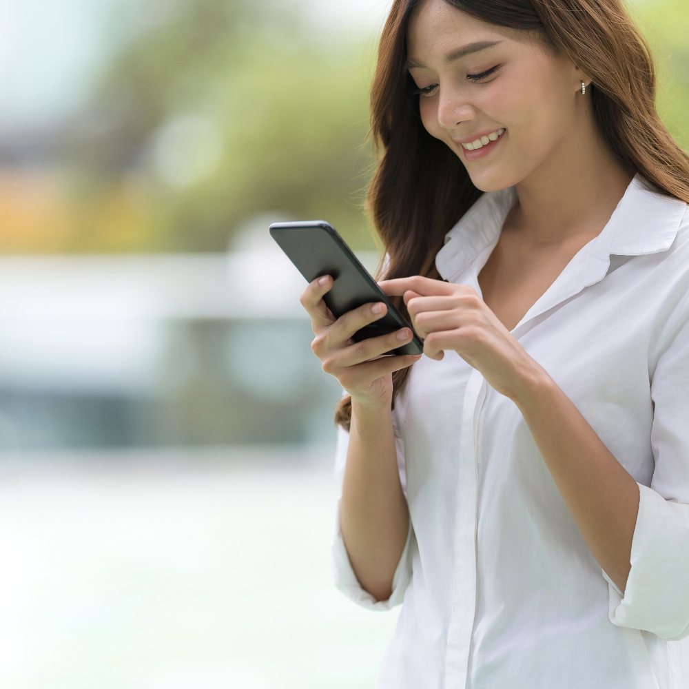 Jeune femme dans la rue qui transmets ses justificatifs de soins depuis l'application mobile pour obtenir ses remboursements