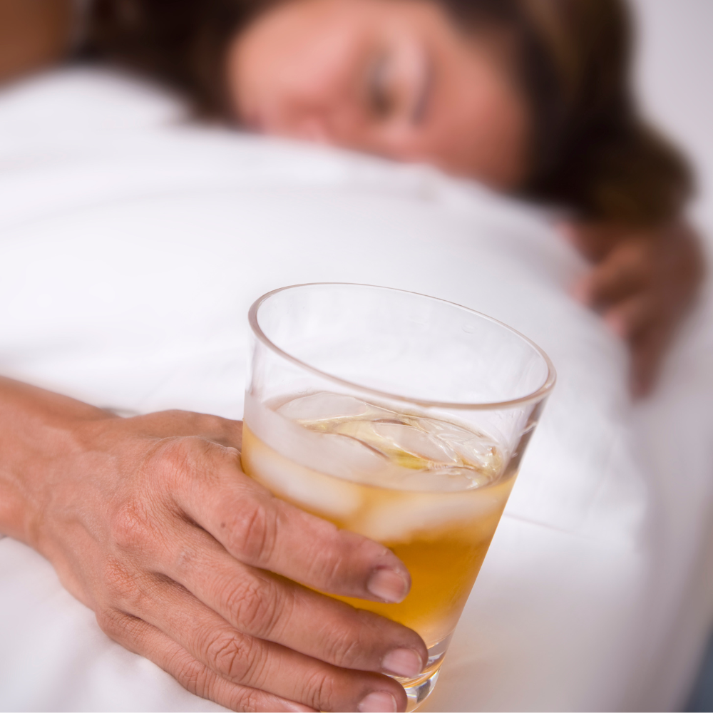 jeune femme tombant de sommeil avec son verre d'alcool à la main