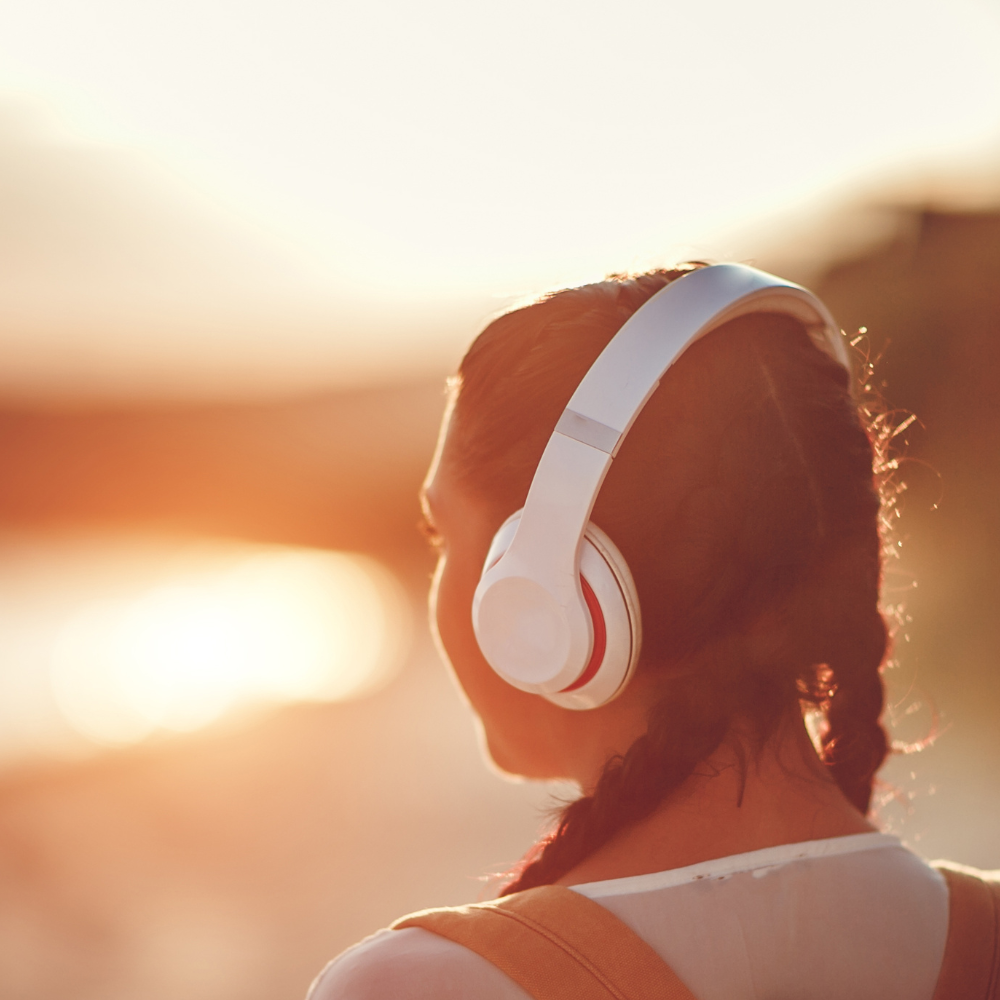Jeune femme regardant la mer au lmoin en eécoutant de la musique tout en veillant à limiter le son de ses écouteurs