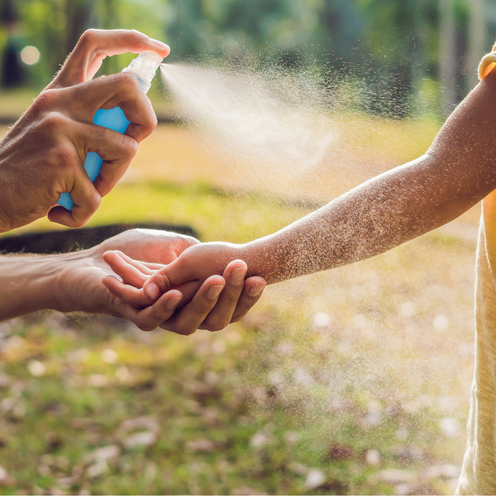 Homme vaporisant le bras de son enfant de produits anti-moustiques pour éviter les piqures lors de balade dans les bois en été