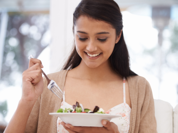jeune femme souriante dégustant une salade équilibrée pour une alimentation saine