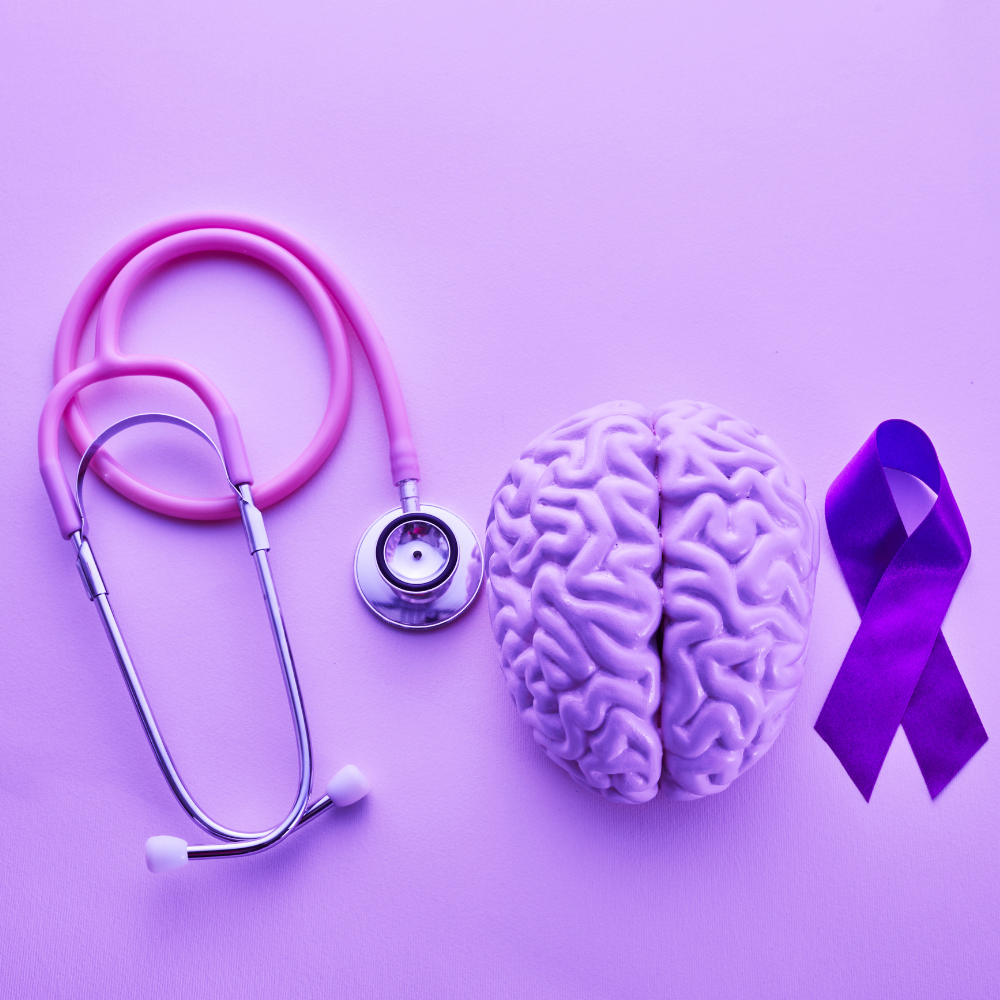 Composition à plat d'une maquette de cerveau humain, d'un stéthoscope rose et d'un ruban violet sur un fond lavande épuré.